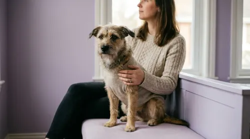Matching dog and owner outfits in oatmeal knit, worn by a calm mixed-breed dog beside its owner at a soft-lit window